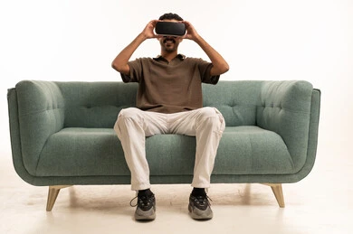 شاب سعودي يستخدم نظارة الواقع الافتراضي على الأريكة