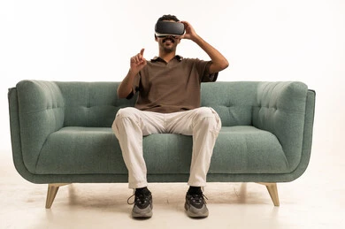 شاب عربي يستخدم نظارة الواقع الافتراضي على الأريكة