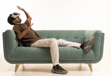 Arab Man Using VR Headset on Sofa White Background