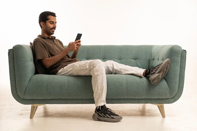 Saudi Man Using Smartphone on Teal Sofa