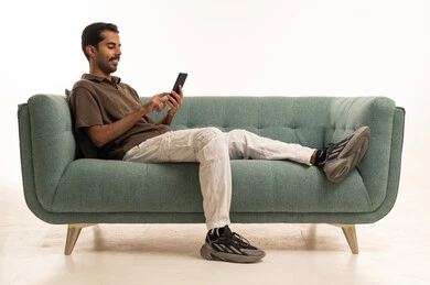 Saudi Man Using Smartphone on Modern Teal Sofa