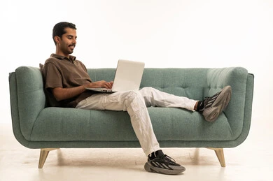 رجل سعودي يستخدم الكمبيوتر المحمول على الأريكة