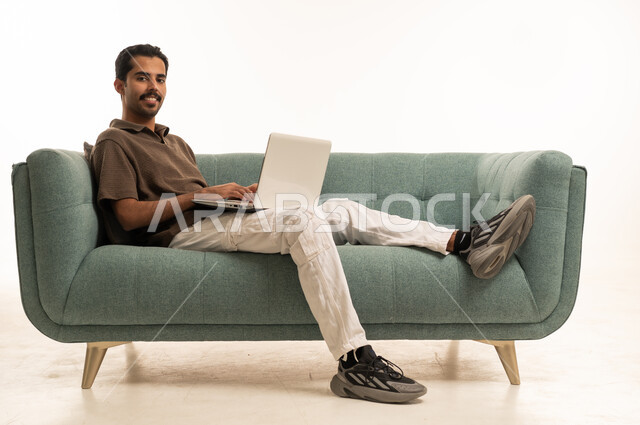 Saudi Man Working on Laptop on Modern Green Sofa