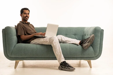 رجل سعودي يعمل على اللابتوب فوق أريكة خضراء