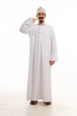 رجل عماني بالزي التقليدي يشير إلى ابتسامته