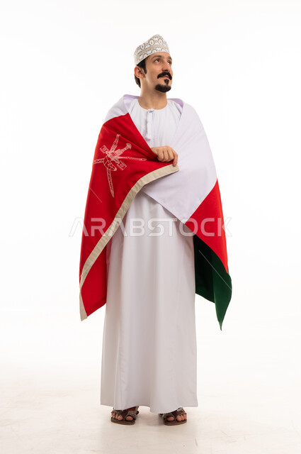 رجل عماني بالعلم الوطني والزي التقليدي