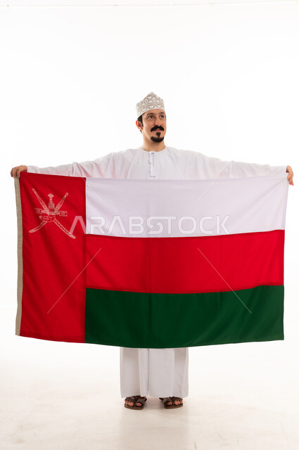 رجل عماني يحمل العلم الوطني على خلفية بيضاء