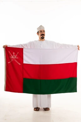 رجل عماني يحمل العلم الوطني على خلفية بيضاء