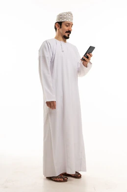رجل عماني بالزي التقليدي يستخدم الهاتف الذكي