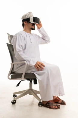 رجل عماني يرتدي نظارة الواقع الافتراضي على كرسي مكتب