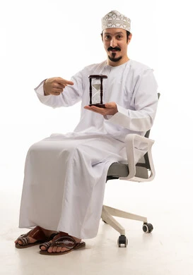 رجل عماني مع ساعة رملية على كرسي مكتب أبيض