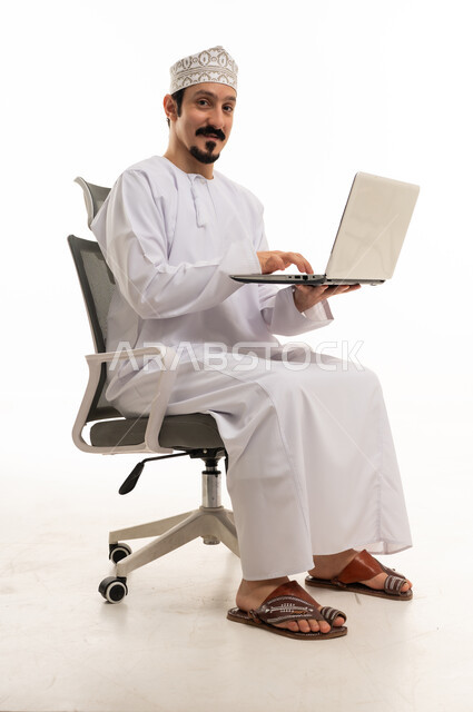 رجل عماني يستخدم لابتوب على كرسي مكتب