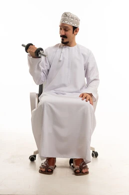 رجل عماني يمارس الرياضة بالدامبل على كرسي مكتب