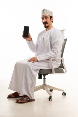 رجل عماني بالزي التقليدي يحمل هاتف ذكي