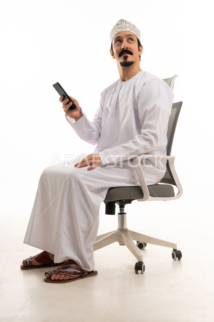 رجل عماني مع هاتف ذكي على كرسي مكتب