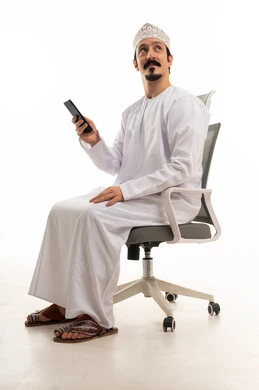 رجل عماني مع هاتف ذكي على كرسي مكتب