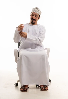 رجل عماني بالزي التقليدي يجلس على كرسي مكتب