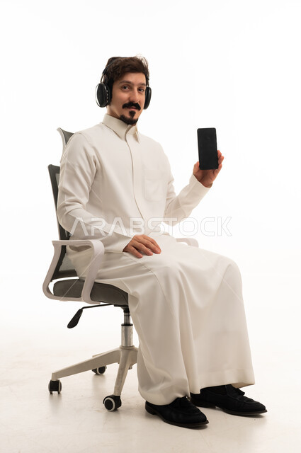رجل سعودي يرتدي سماعات ويحمل هاتفا ذكيا