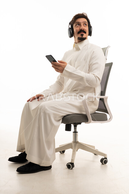 رجل عربي يرتدي سماعات على كرسي مكتب