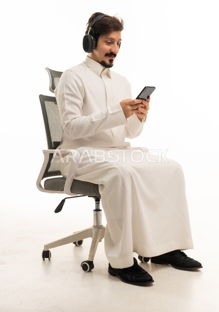 Saudi Man with Headphones and Smartphone in Office Chair