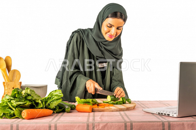 Portrait of a Saudi Gulf woman, standing in front of a table with a group of fresh vegetables, making a video call via a laptop, sharing preparing recipes on social media, preparing salads and healthy dishes, the concept of a healthy diet, live broadcast