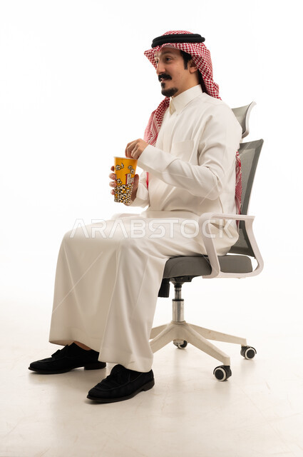 رجل سعودي بالزي التقليدي يأكل الفشار