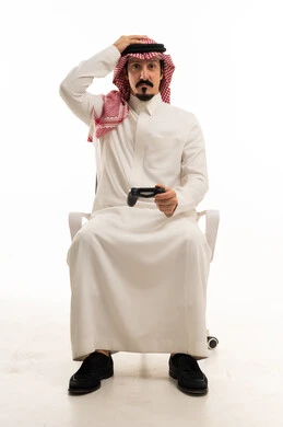 رجل سعودي يمسك جهاز تحكم ألعاب بتعبير خيبة أمل