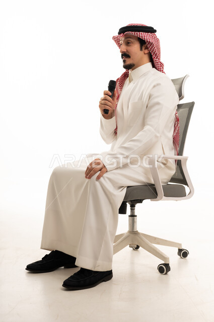رجل سعودي يحمل ميكروفون على كرسي مكتب