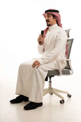 رجل سعودي يحمل ميكروفون على كرسي مكتب