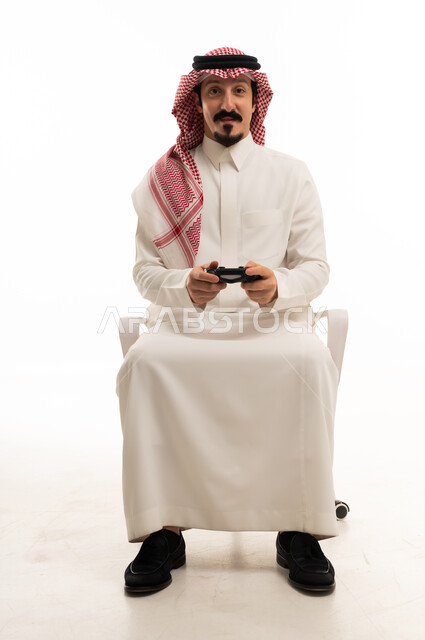 رجل سعودي يمسك بجهاز تحكم ألعاب الفيديو بخلفية بيضاء