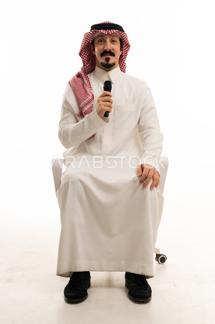 Saudi Man Holding Microphone Sitting in Studio Setting