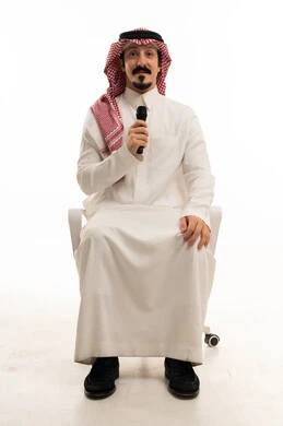 Saudi Man Holding Microphone Sitting in Studio Setting
