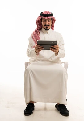 رجل سعودي يستخدم جهازاً لوحياً على خلفية بيضاء