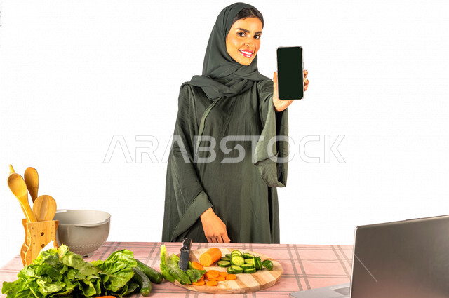 بورتريه لمرأة خليجية سعودية، تقف أمام طاولة عليها مجموعة من الخضراوات الطازجة، تعرض شاشة سوداء، عرض خدمات وتطبيقات عبر الجوال، إستخدام جهاز الحاسوب المحمول، مشاركة تحضير الوصفات على مواقع التواصل الاجتماعي، إعداد الأطباق الصحية، مفهوم الإعلانات