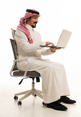 رجل أعمال سعودي يستخدم اللابتوب على كرسي مكتب