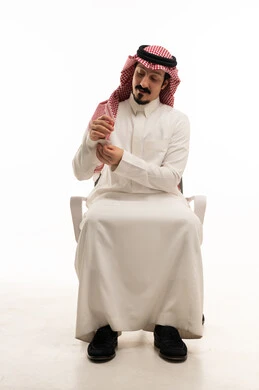 رجل سعودي بالثوب التقليدي يعدل هندامه في استوديو