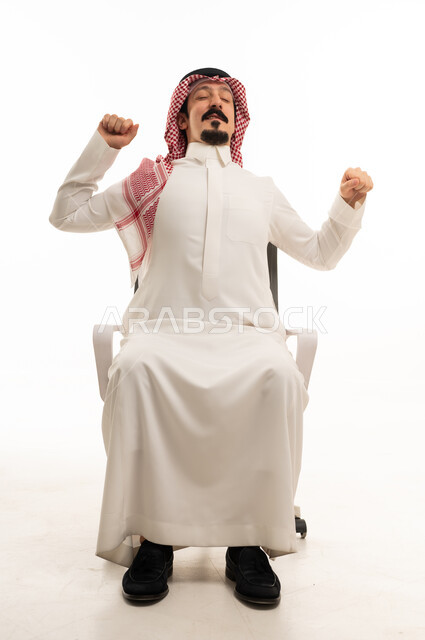 رجل سعودي يسترخي ويمدد ذراعيه في المكتب