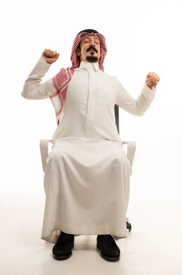 رجل سعودي يسترخي ويمدد ذراعيه في المكتب