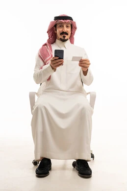 رجل سعودي يحمل هاتفاً وبطاقة على خلفية بيضاء