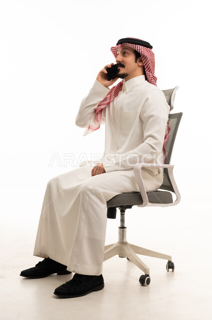 رجل أعمال سعودي جالس على كرسي يتحدث بالهاتف