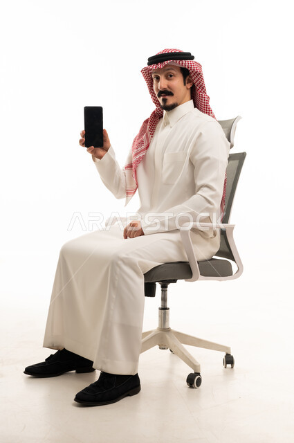 رجل سعودي بالثوب التقليدي يحمل هاتف ذكي