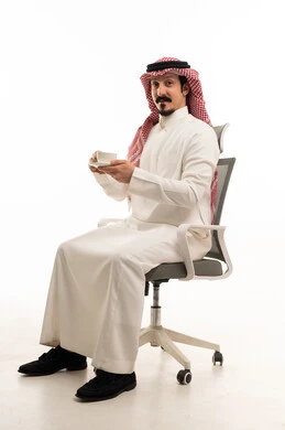 رجل سعودي بالثوب التقليدي يجلس على كرسي مكتب