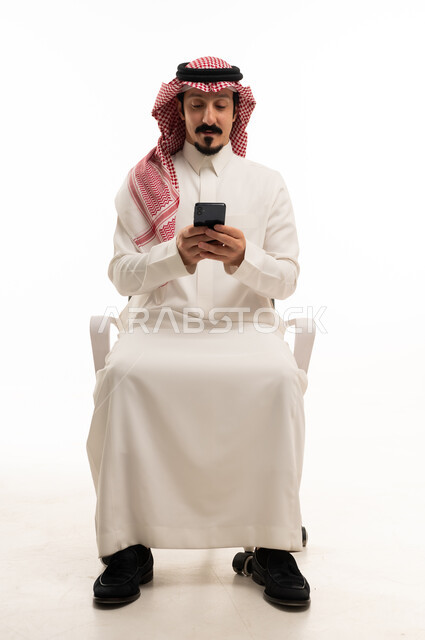 Saudi Man Sitting in Chair Using Smartphone