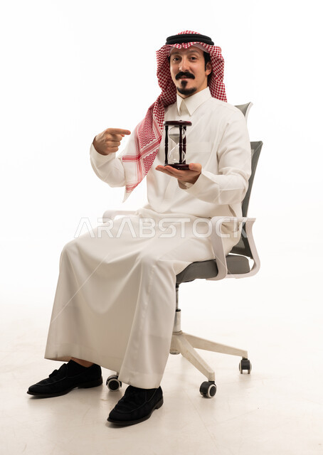رجل أعمال سعودي مع ساعة رملية بخلفية بيضاء