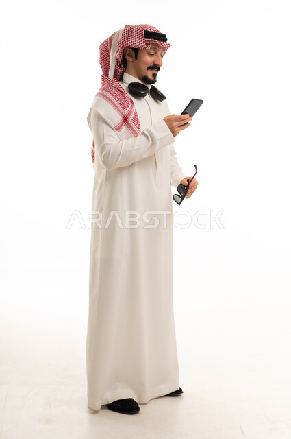 Saudi Man in Traditional Thobe Using Smartphone