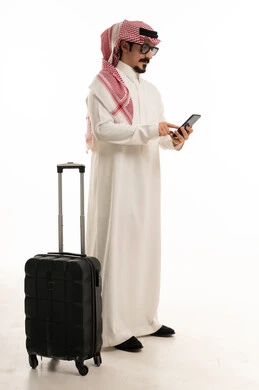 رجل سعودي مع حقيبة سفر يستخدم الهاتف الذكي