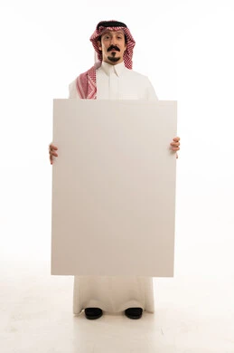 رجل سعودي يحمل لوحة بيضاء فارغة بخلفية استوديو
