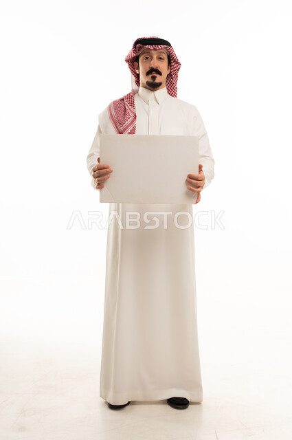 رجل سعودي يحمل لوحة بيضاء فارغة في الاستوديو