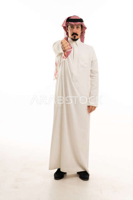 رجل سعودي يشير بالإبهام للأسفل على خلفية بيضاء