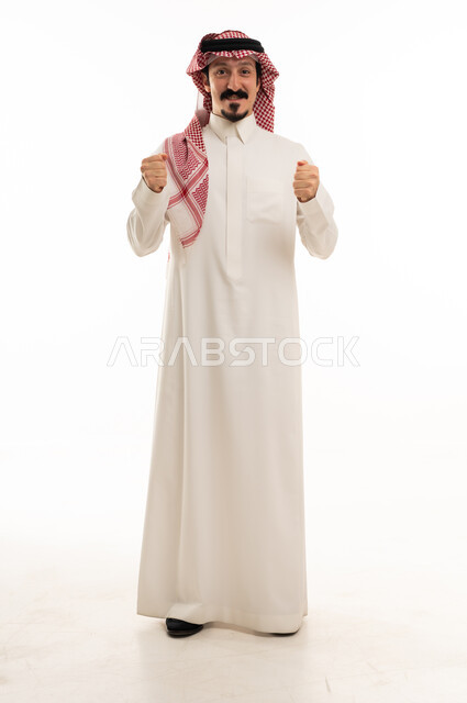 رجل سعودي بالثوب التقليدي يرفع قبضتيه نجاح